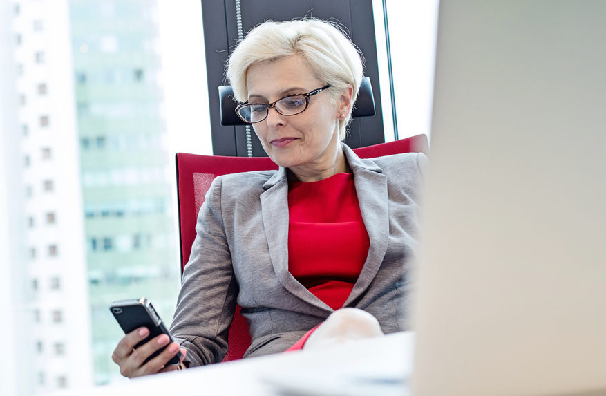 Mature Businesswoman Using Mobile Phone At Desk In Office Sparcstart